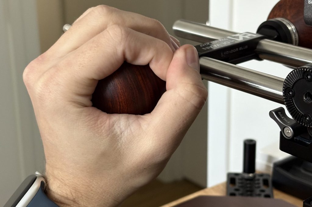 Cinematographer holding a wooden ball camera handle, demonstrating comfortable ergonomic grip